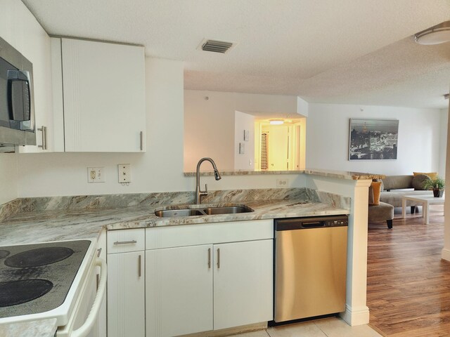 kitchen featuring light stone countertops, stainless steel appliances, light hardwood / wood-style floors, sink, and a textured ceiling