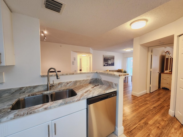 kitchen with a textured ceiling, light hardwood / wood-style flooring, dishwasher, light stone counters, and sink