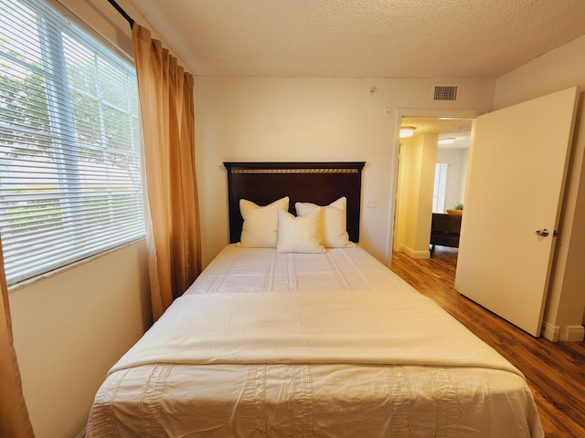 bedroom with a textured ceiling and hardwood / wood-style floors