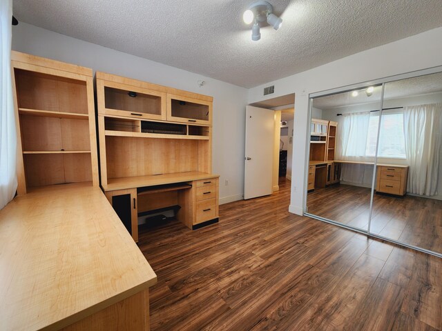 unfurnished office with dark wood-type flooring and a textured ceiling