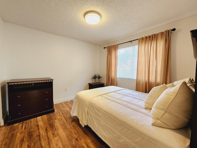 bedroom with a textured ceiling and wood-type flooring