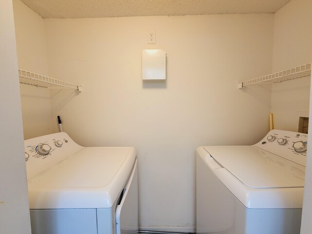 laundry room with a textured ceiling and washer and clothes dryer