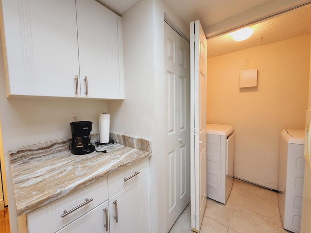 laundry area featuring a textured ceiling, separate washer and dryer, and light tile patterned floors