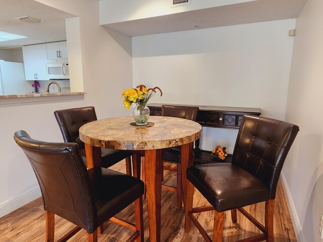 dining room featuring a textured ceiling and light hardwood / wood-style floors