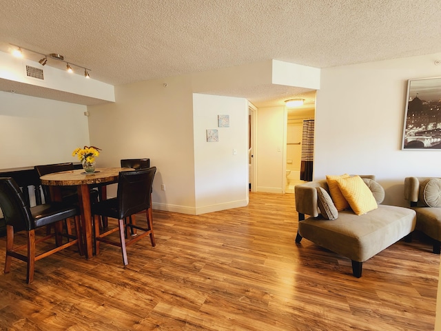 dining space with light hardwood / wood-style floors and a textured ceiling