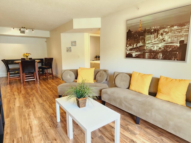 living room featuring a textured ceiling, rail lighting, and hardwood / wood-style floors