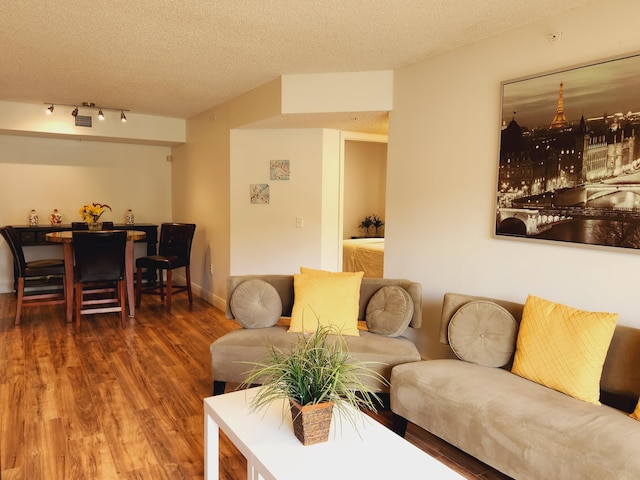 living area with baseboards, a textured ceiling, and wood finished floors