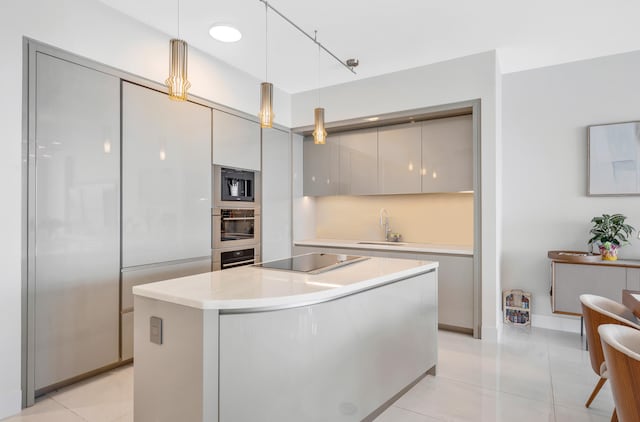 kitchen with track lighting, black appliances, sink, light tile patterned floors, and a center island