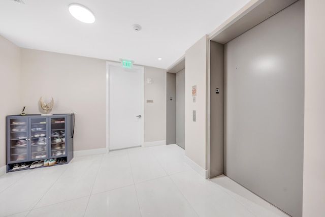 corridor with tile patterned flooring and elevator