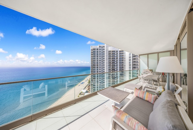 balcony with a water view, a beach view, and an outdoor living space