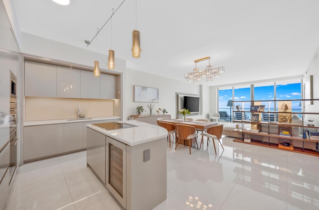 kitchen with pendant lighting, sink, stainless steel microwave, light tile patterned flooring, and black electric cooktop