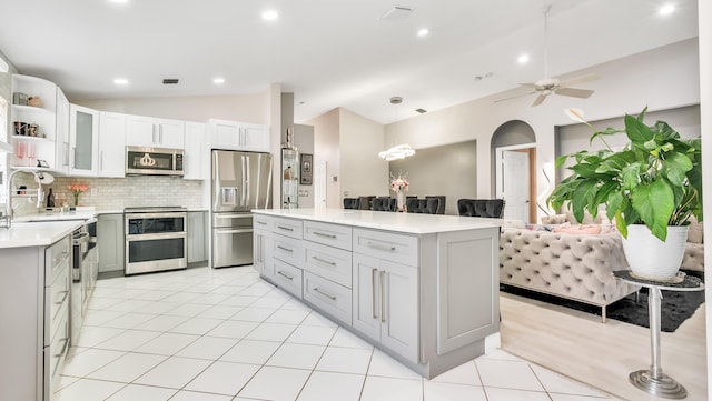 kitchen with appliances with stainless steel finishes, vaulted ceiling, tasteful backsplash, pendant lighting, and ceiling fan