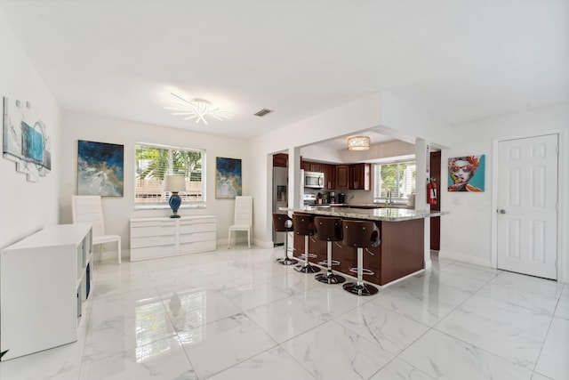 kitchen with visible vents, a kitchen bar, light countertops, appliances with stainless steel finishes, and marble finish floor