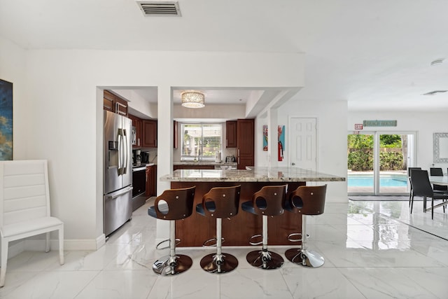 kitchen with visible vents, marble finish floor, a breakfast bar, and stainless steel appliances