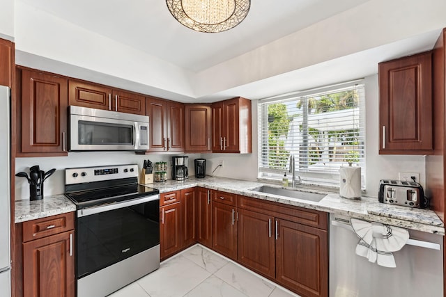 kitchen with a sink, light stone countertops, marble finish floor, and appliances with stainless steel finishes