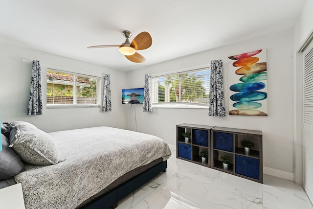 bedroom featuring a closet, marble finish floor, baseboards, and multiple windows