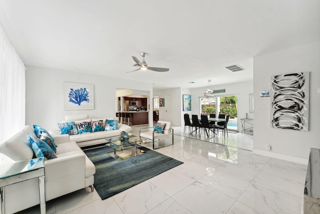 living area featuring visible vents, baseboards, marble finish floor, and ceiling fan