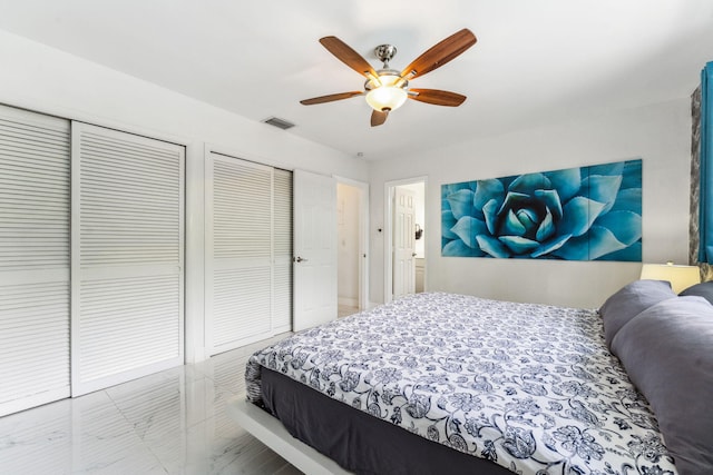 bedroom with a ceiling fan, visible vents, and two closets