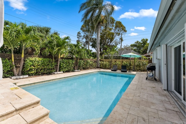 view of swimming pool with a patio area, area for grilling, a fenced backyard, and a fenced in pool