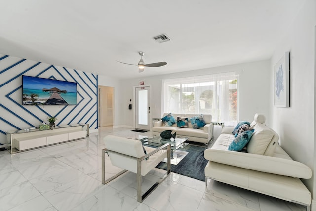 living area with visible vents, marble finish floor, a ceiling fan, wallpapered walls, and an accent wall