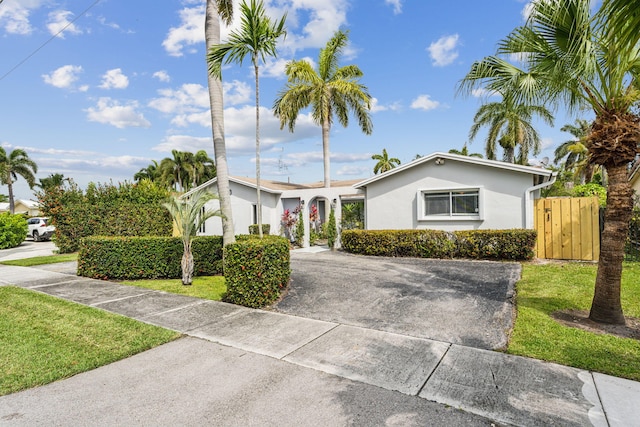 view of front facade featuring a front yard, a gate, driveway, and stucco siding