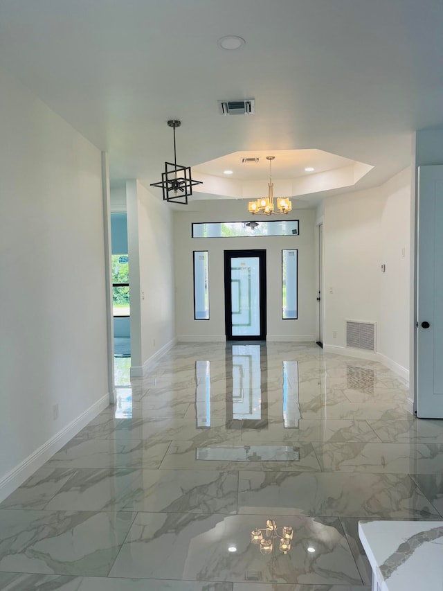 tiled empty room with an inviting chandelier and a raised ceiling