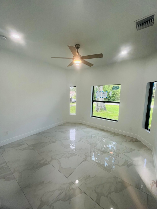 tiled spare room with ceiling fan and a wealth of natural light