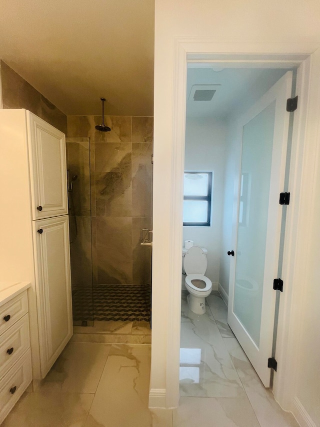 bathroom featuring tile patterned floors, a shower with shower door, and toilet