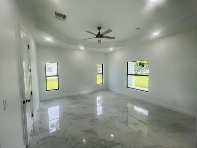 unfurnished room with ceiling fan, a raised ceiling, and light tile patterned floors