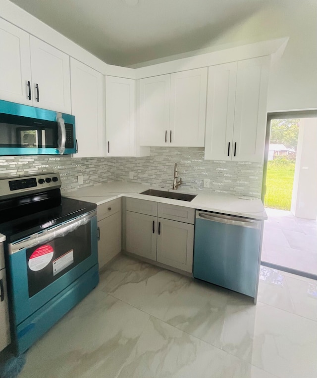 kitchen featuring light tile patterned flooring, white cabinets, stainless steel appliances, decorative backsplash, and sink