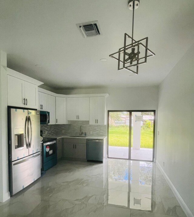 kitchen with stainless steel appliances, light tile patterned floors, decorative backsplash, white cabinetry, and a chandelier