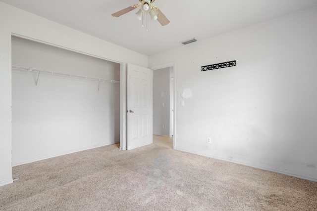 unfurnished bedroom with ceiling fan, a closet, and light carpet