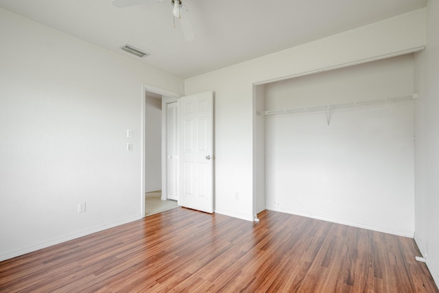 unfurnished bedroom featuring ceiling fan, a closet, and hardwood / wood-style flooring