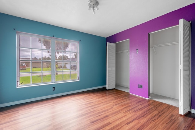 unfurnished bedroom featuring multiple closets and wood-type flooring