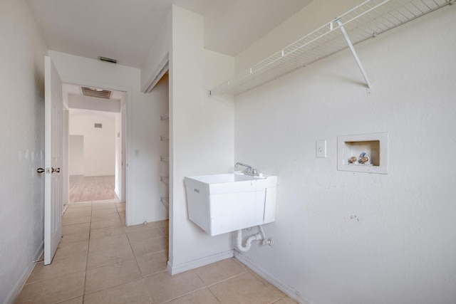 laundry room featuring washer hookup, sink, and light tile patterned flooring