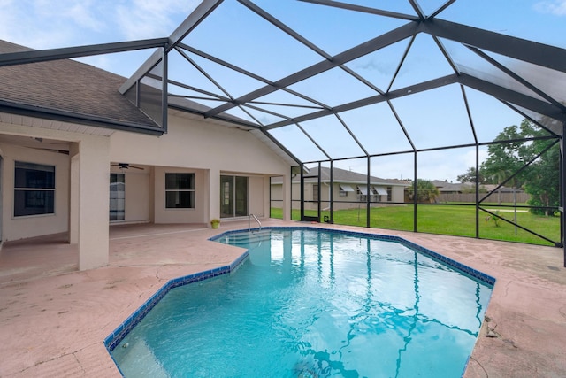 view of pool with a yard, glass enclosure, ceiling fan, and a patio