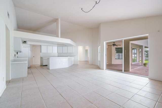 unfurnished living room with lofted ceiling, ceiling fan, and light tile patterned floors