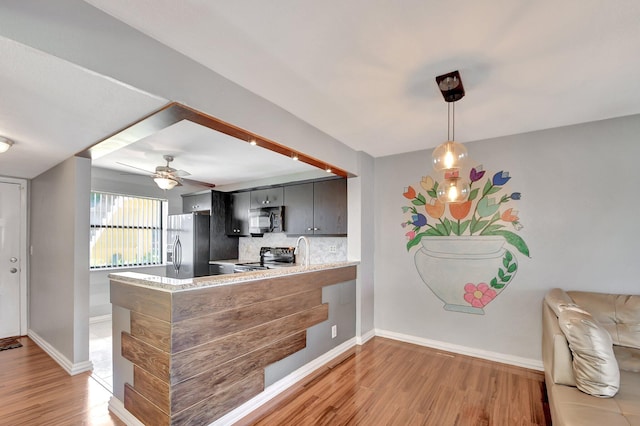 kitchen with backsplash, stainless steel appliances, kitchen peninsula, and light wood-type flooring