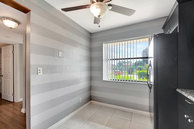 tiled empty room featuring ceiling fan