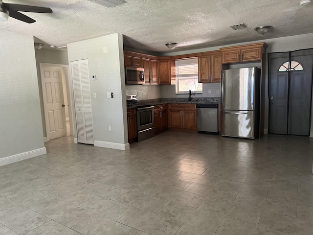 kitchen with ceiling fan, appliances with stainless steel finishes, sink, and a textured ceiling