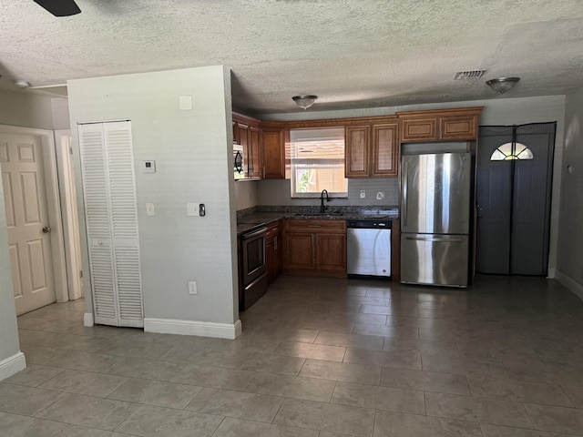 kitchen with a textured ceiling, sink, stainless steel appliances, and tile patterned floors