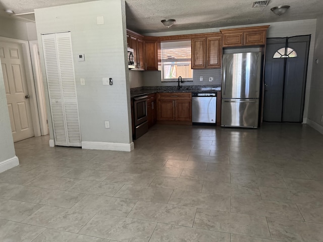 kitchen featuring a textured ceiling, appliances with stainless steel finishes, and light tile patterned floors