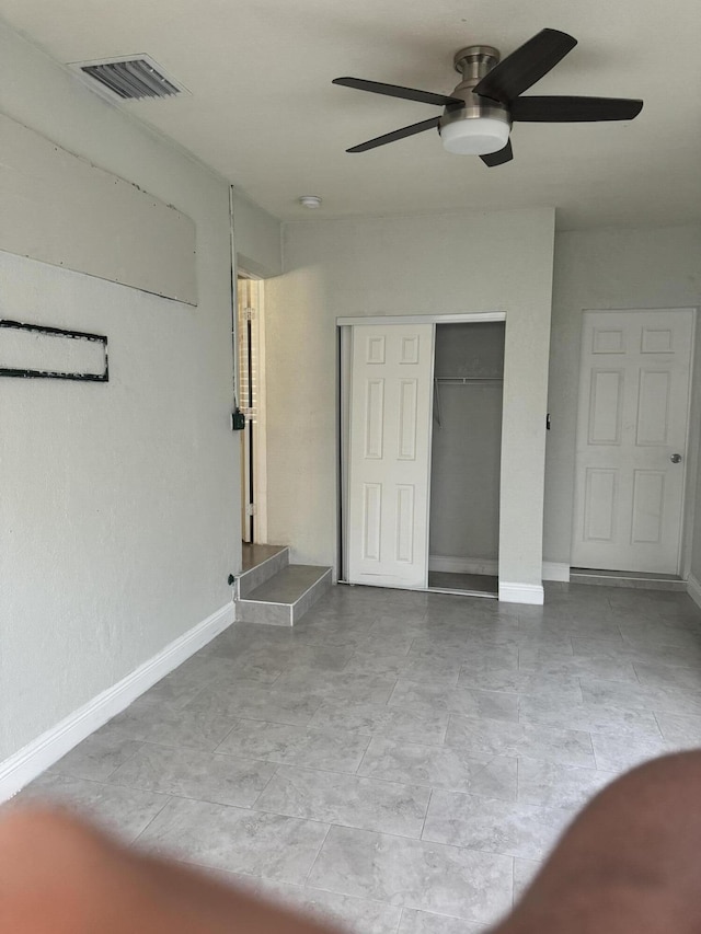 unfurnished bedroom with ceiling fan and a closet