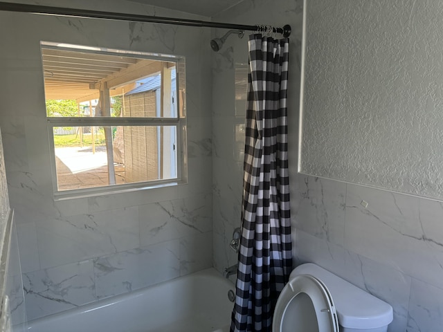 bathroom featuring tile walls, toilet, and shower / tub combo with curtain