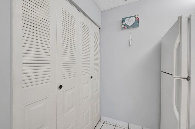 kitchen featuring light tile patterned flooring, white fridge, and a textured ceiling