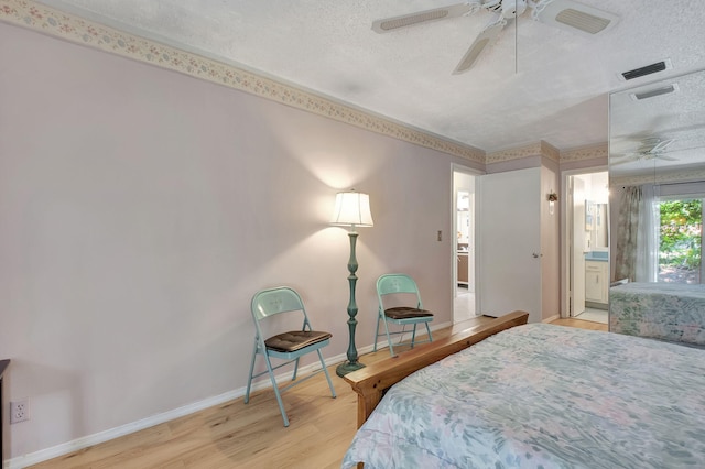 bedroom featuring ensuite bathroom, light wood-type flooring, ceiling fan, and a textured ceiling