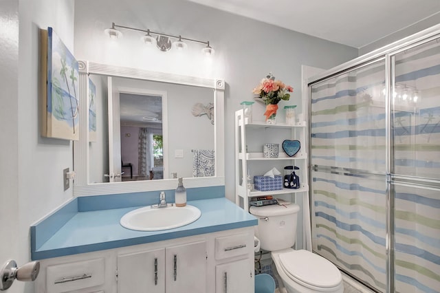 bathroom with a shower with door, vanity, and toilet