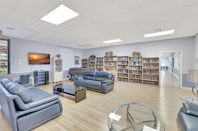 living room with light hardwood / wood-style flooring and a drop ceiling