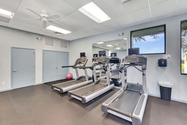 workout area featuring a drop ceiling, concrete flooring, and ceiling fan