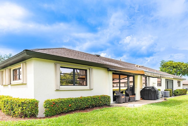 rear view of house featuring a lawn, a patio, and central air condition unit